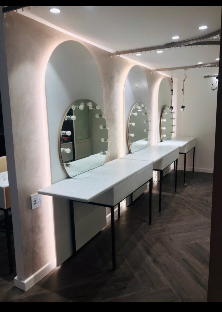 Arched bays, backlit mirrors and warm downlights for a working salon.